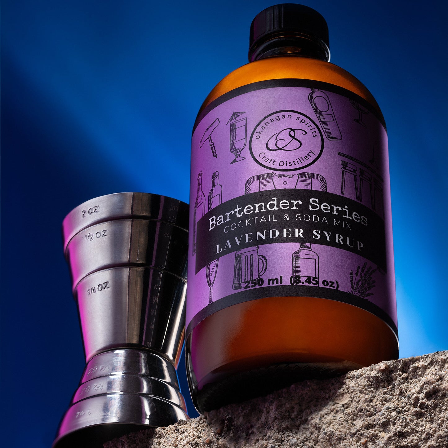 Bottle of Lavender Syrup with a cocktail shaker against a blue sky
