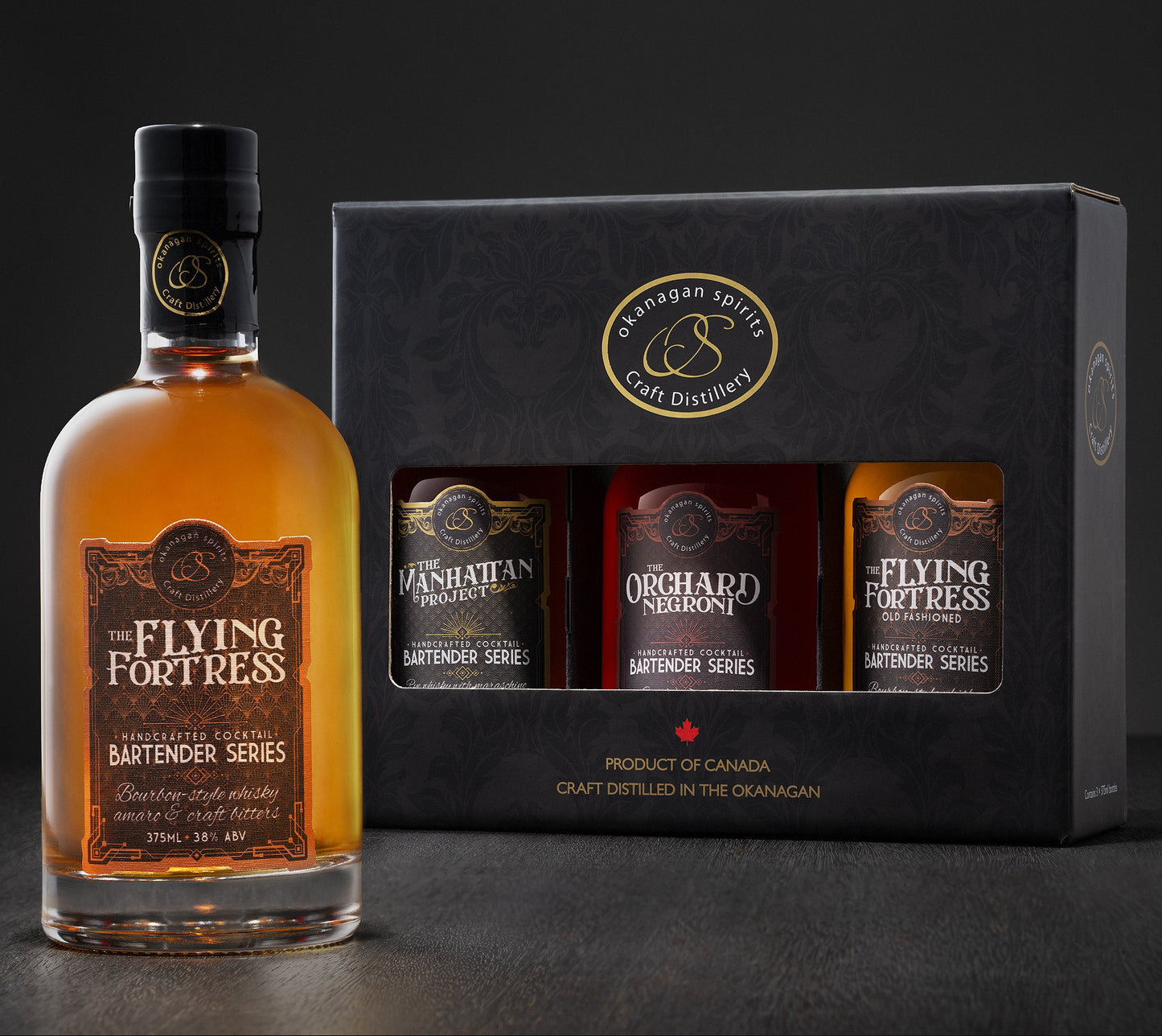 A bottle of The Flying Fortress Bartender Series Old Fashioned Pre-batched cocktail alongside its black gift box containing three Mickey sized bottles: Manhattan, Negroni, and the Flying Fortress Old Fashioned. The products are shown on a dark studio background.